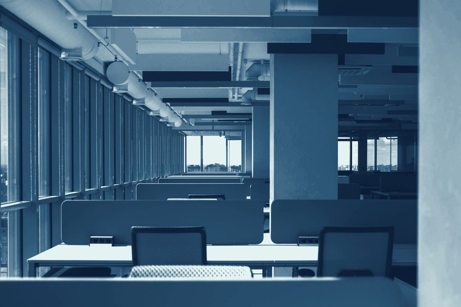 Rows of empty desks in an open-plan office after hours